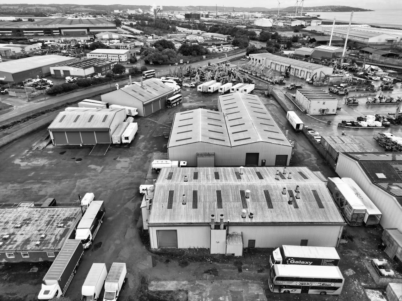 A monochrome aerial shot of an industrial area in England with warehouses and trucks.